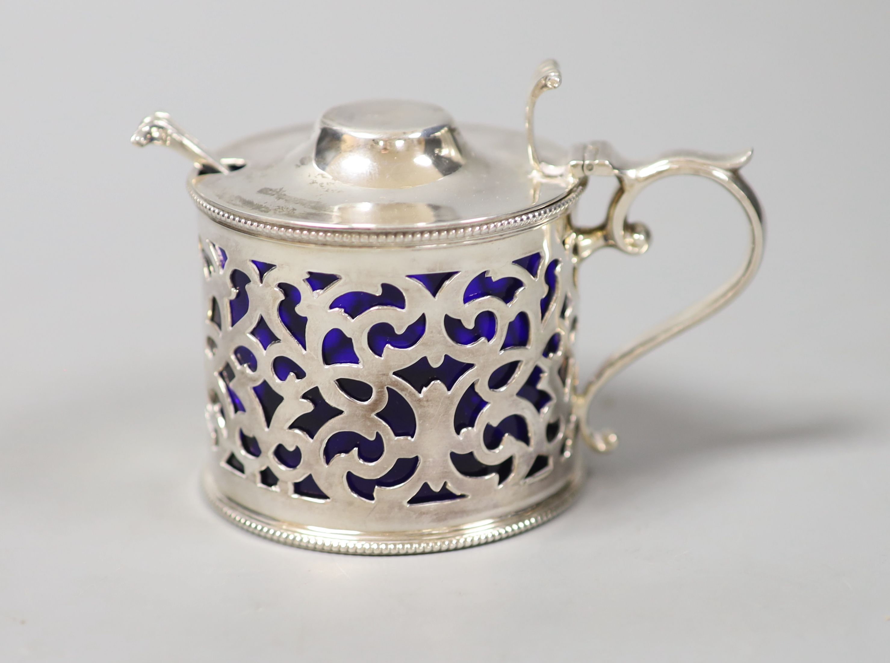 A Victorian silver cylindrical mustard pot with fretwork sides, Sheffield 1899, 74mm and a later spoon